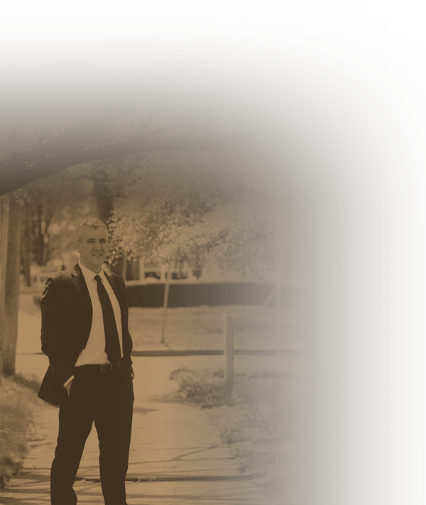 Attorney walking outdoors on a tree-lined sidewalk