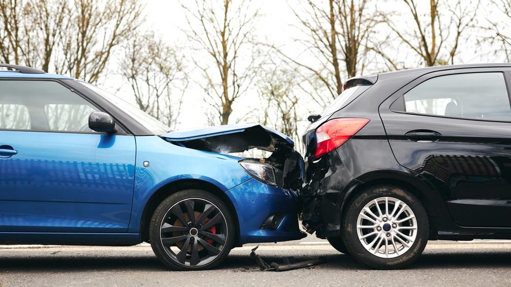 A blue car causes a rear-end collision with a stationary vehicle, leaving the driver to wonder how long they have to report a car accident to insurance.