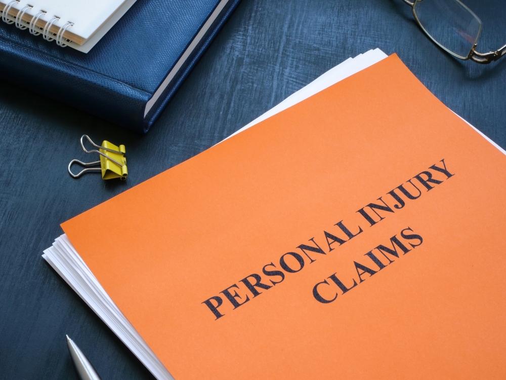 Folder with “Personal Injury Claims” written on it, with someone nearby wondering if they can file a personal injury claim if they were injured in a bar shooting