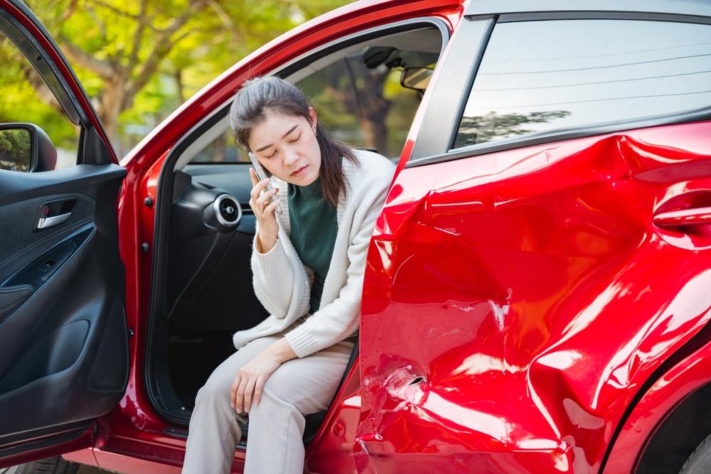 Woman sits in damaged car and calls lawyer to discuss getting traffic camera footage in Stamford.